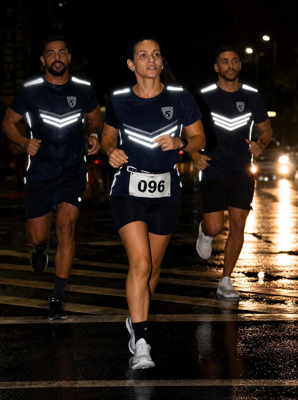 Corrida noturna com corredores usando detalhes refletivos brilhando no farol e no flash